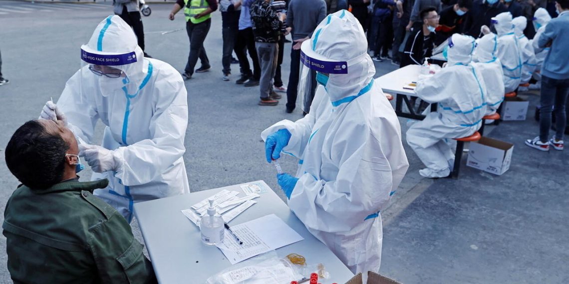 A medical worker in protective suit collects a swab from a resident at a makeshift nucleic acid testing site, following cases of the coronavirus disease (COVID-19) in Shanghai, China March 11, 2022. Picture taken March 11, 2022. cnsphoto via REUTERS   ATTENTION EDITORS - THIS IMAGE WAS PROVIDED BY A THIRD PARTY. CHINA OUT.