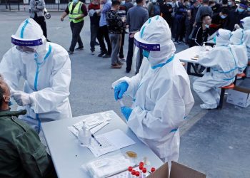A medical worker in protective suit collects a swab from a resident at a makeshift nucleic acid testing site, following cases of the coronavirus disease (COVID-19) in Shanghai, China March 11, 2022. Picture taken March 11, 2022. cnsphoto via REUTERS   ATTENTION EDITORS - THIS IMAGE WAS PROVIDED BY A THIRD PARTY. CHINA OUT.